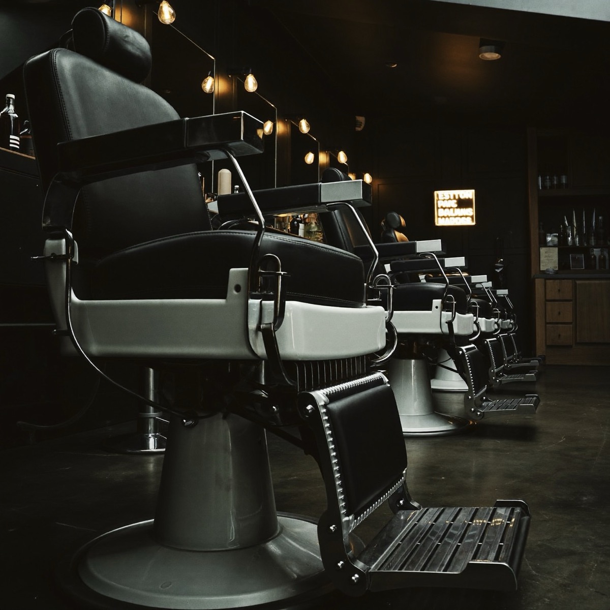 Row of leather barber chairs under warm lights