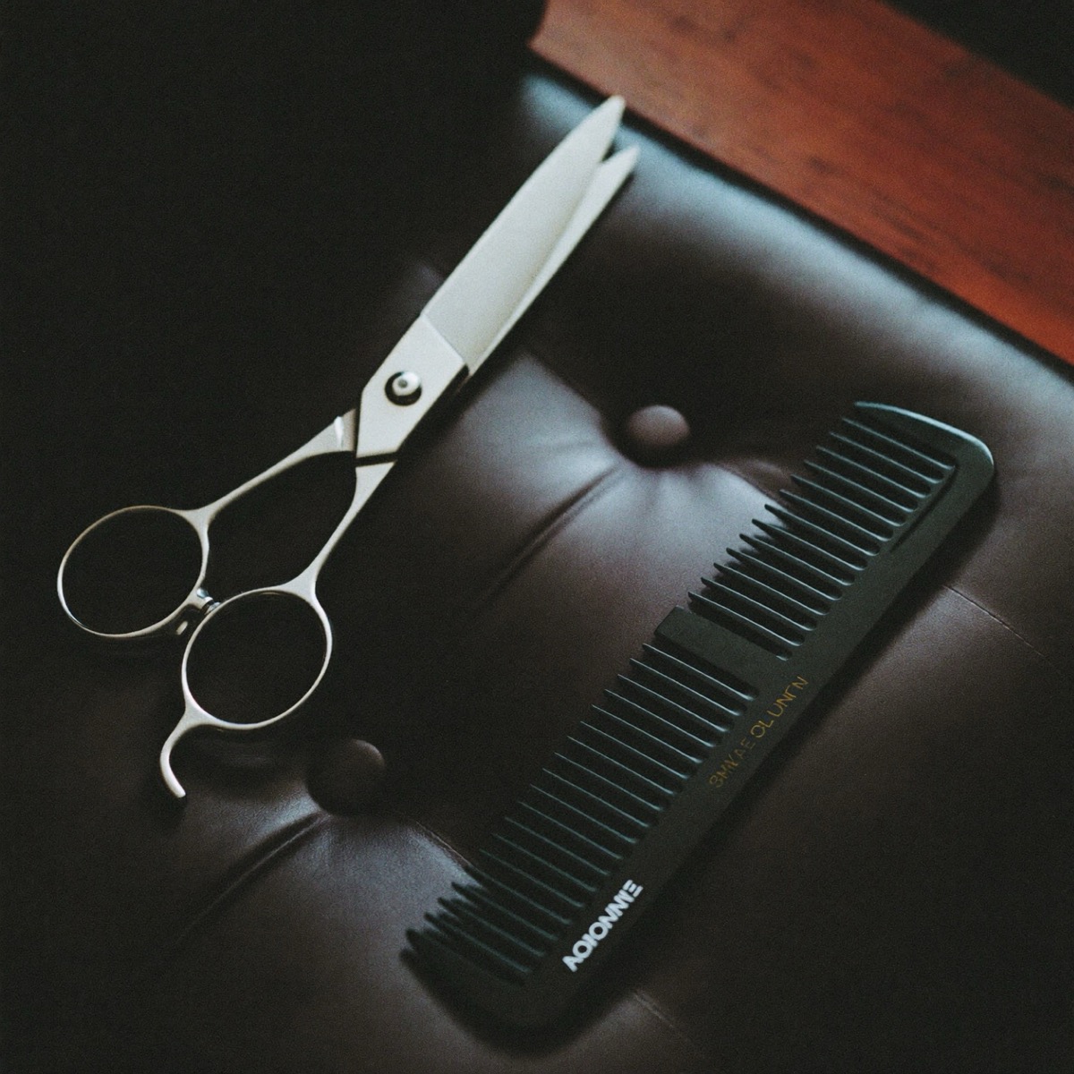 Barber scissors and comb on dark leather